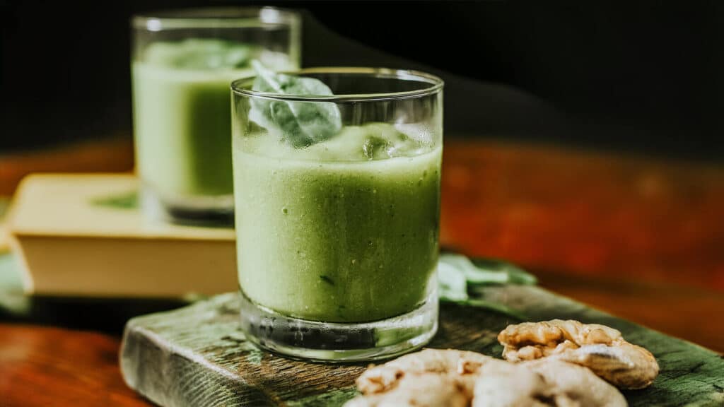 Smoothie verde nutritivo com gengibre e nozes, componente do Super Shake Clássico feito com leite ou leite à base de plantas, whey protein, banana, espinafre, manteiga de amendoim e um toque de canela.